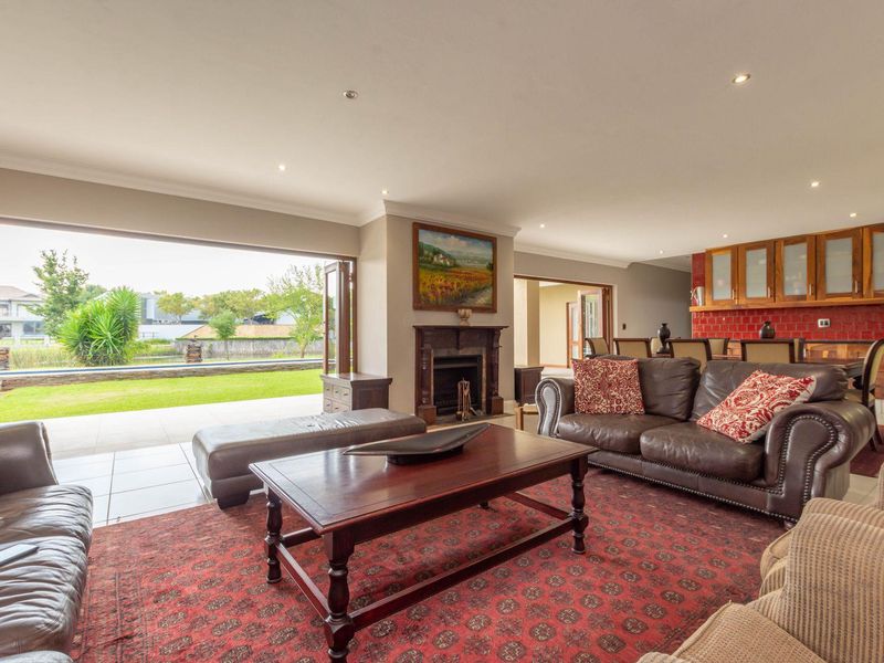 Spacious open-plan living area featuring a traditional fireplace, tiled flooring, and large sliding doors opening to a patio and garden.