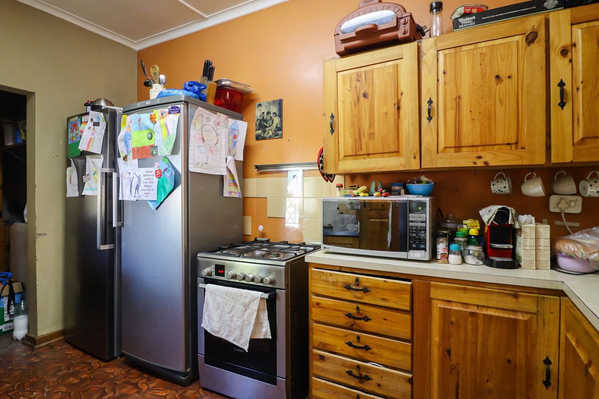 A functional kitchen featuring wooden cabinetry, a freestanding gas stove, and ample counter space, offering a traditional aesthetic with potential for modernization.