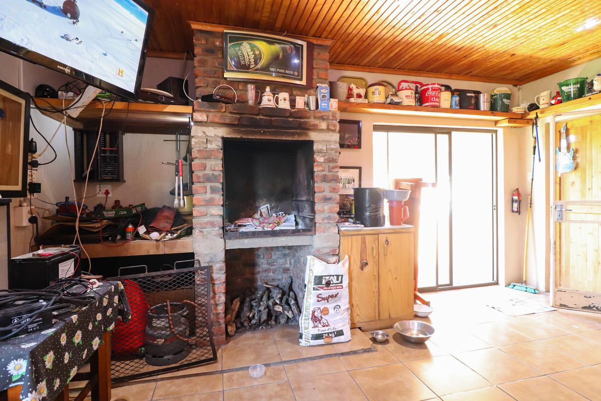 An indoor entertainment area featuring a built-in brick fireplace, tiled flooring, and timber-clad ceiling with sliding door access to the exterior.