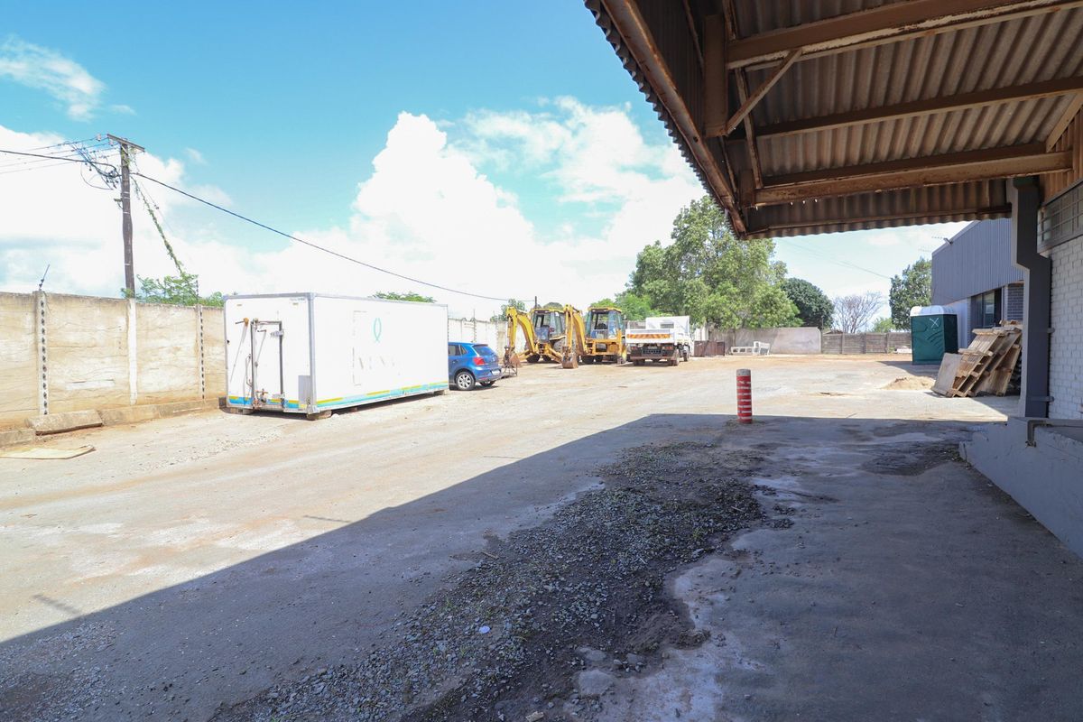 Commercial exterior yard space featuring a covered loading area, concrete surfacing, and perimeter walling, suitable for industrial or storage use.