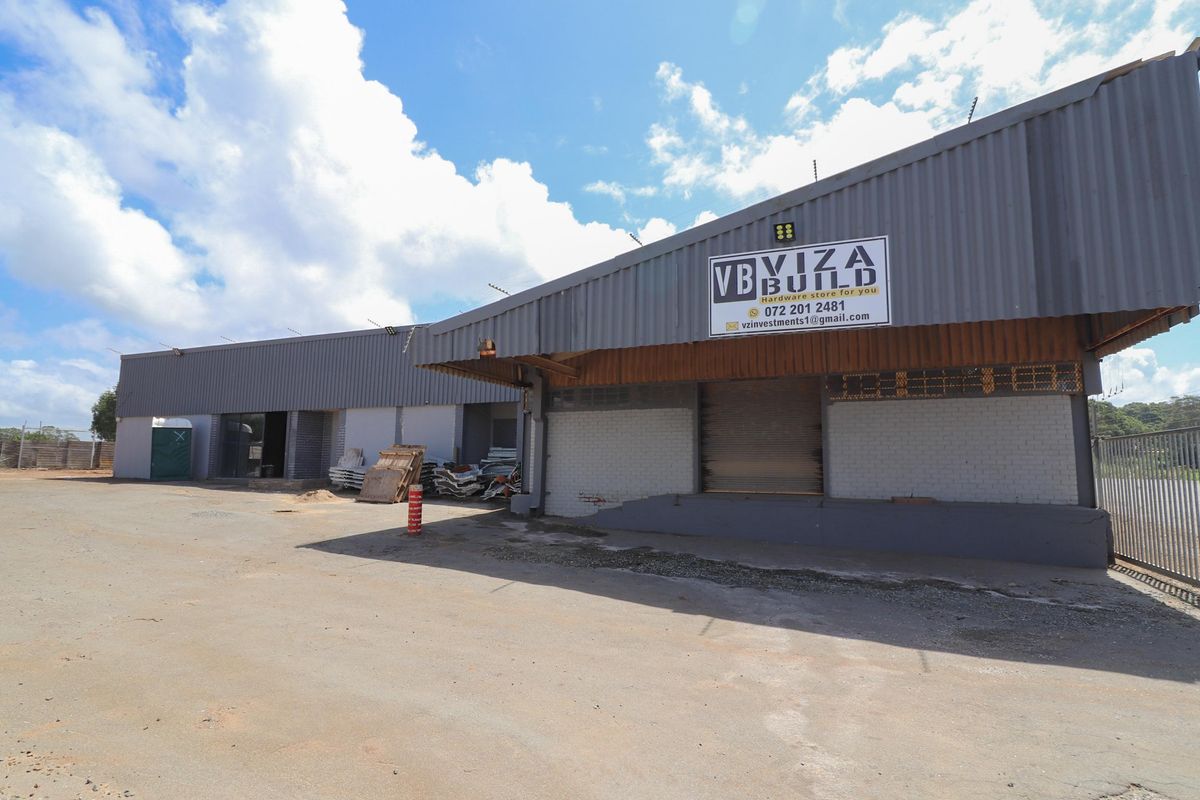 Commercial warehouse facility featuring metal cladding, roller shutter doors, and a paved yard area suitable for logistics or retail operations.