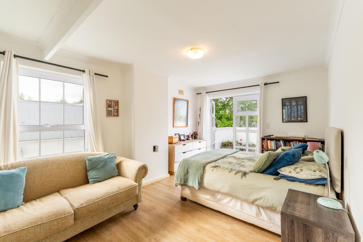 Spacious bedroom featuring laminate flooring, ample natural light, and direct access to a private balcony through glass french doors.