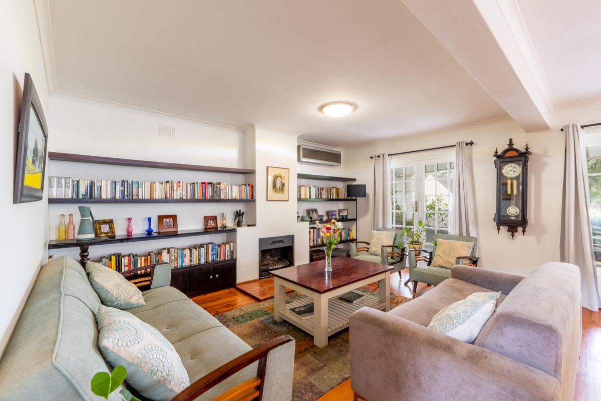 A comfortable living room featuring hardwood floors, built-in shelving, a fireplace, and direct access to the outdoors through classic french doors.
