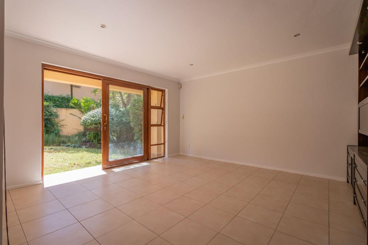 Spacious living room featuring neutral floor tiles, recessed downlighting, and large wooden sliding doors providing direct access to the garden.