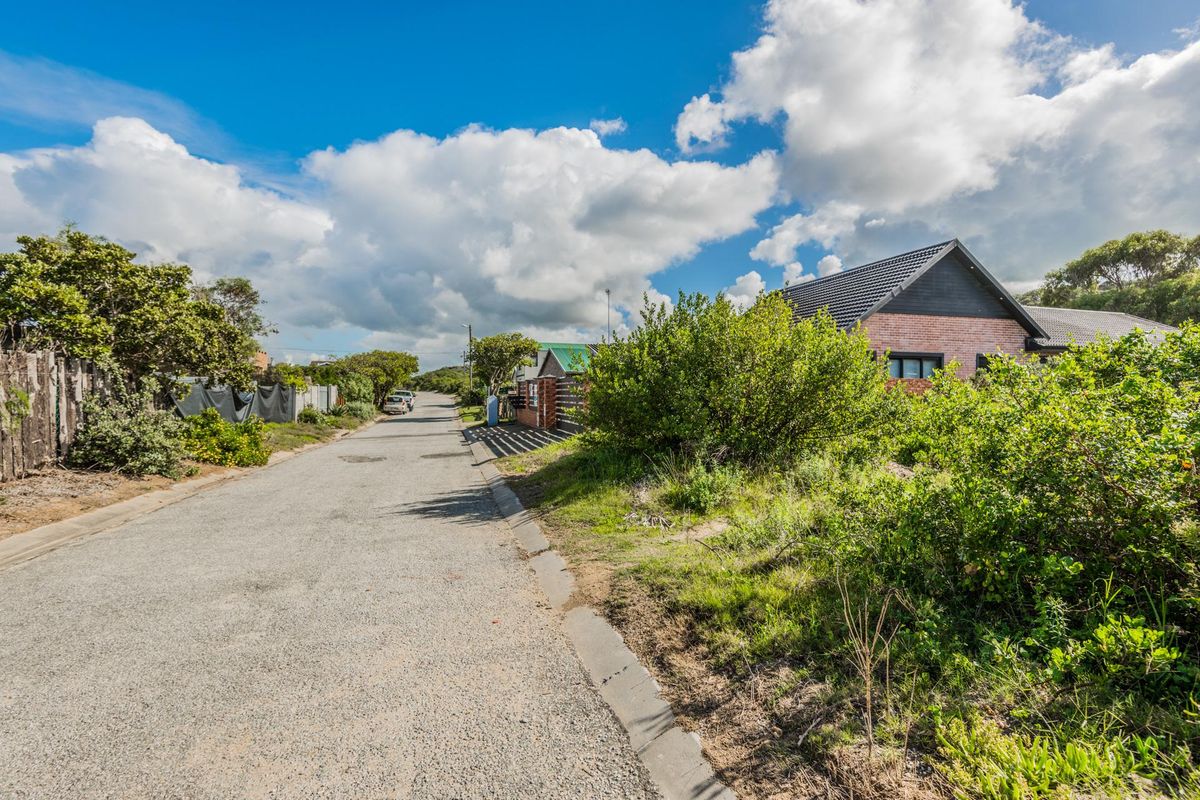 A view of the residential street approach showing the road surface, curbing, and surrounding neighborhood vegetation.