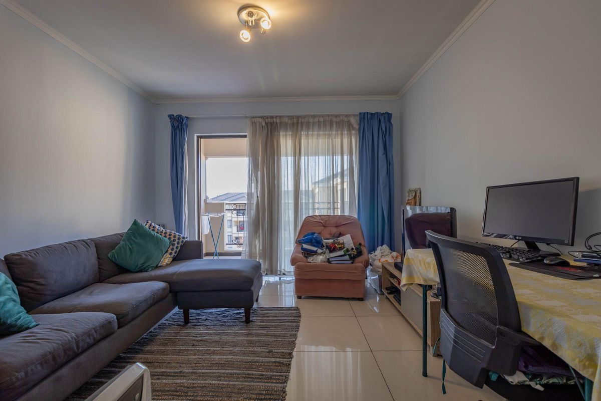 A living room featuring tiled flooring and sliding glass doors that open onto a balcony, providing natural light and access to outdoor space.
