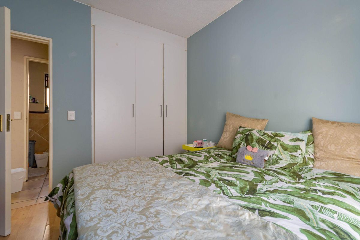 A bedroom featuring built-in wardrobes and a view into an adjacent tiled bathroom.