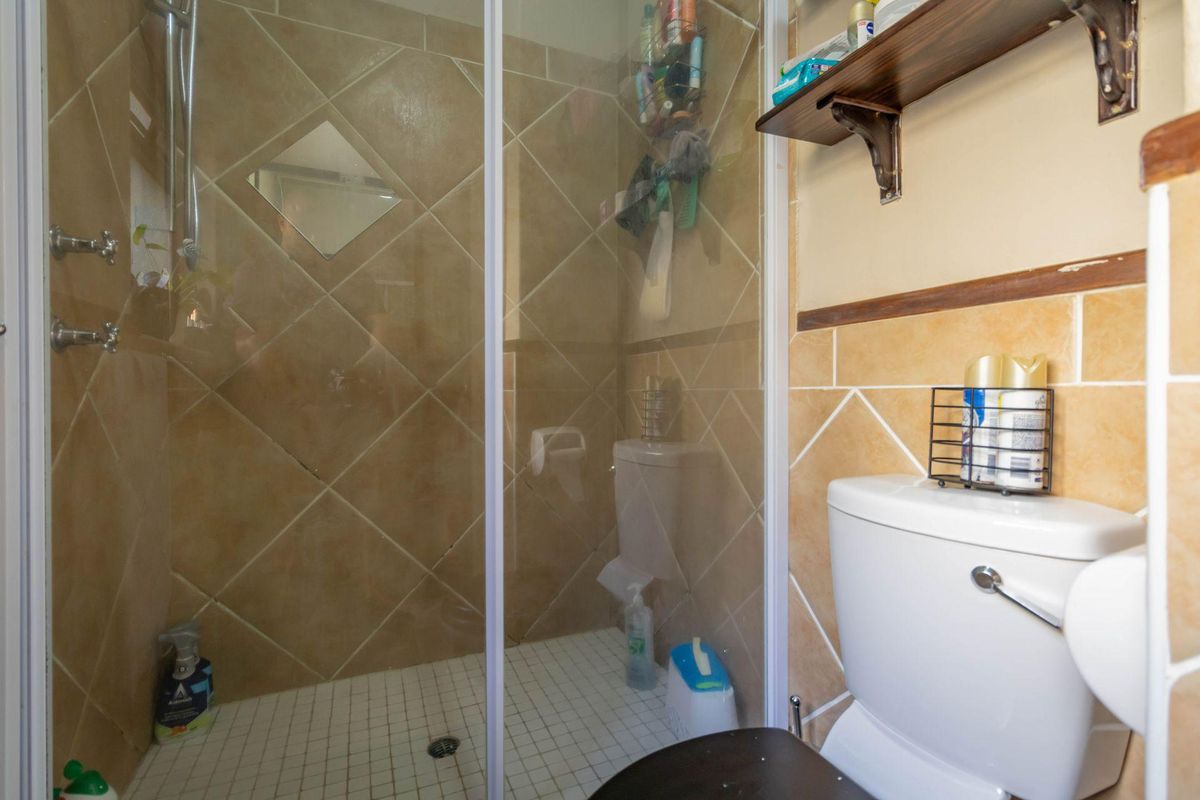 A functional bathroom featuring a glass-enclosed shower with diamond-patterned wall tiles and a standard white toilet.