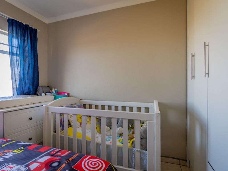 A bedroom featuring built-in cupboards and a window with natural light.