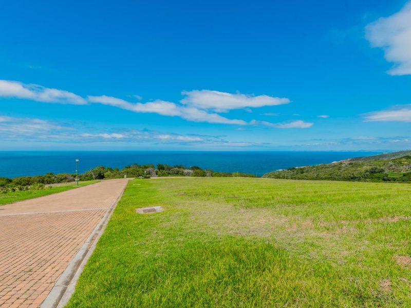 A vacant residential plot featuring a paved driveway and expansive, unobstructed ocean views.