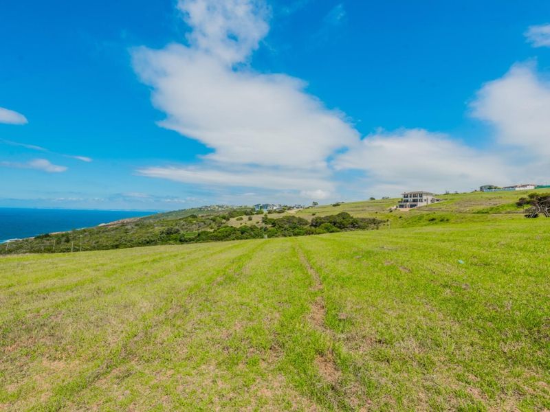 A scenic view of the vacant residential land featuring expansive grassy terrain with coastal and ocean vistas in the background.