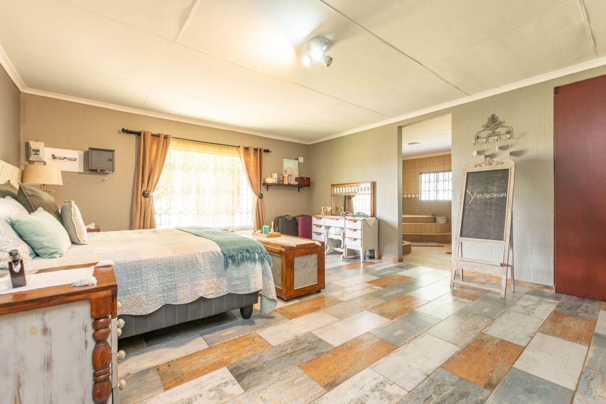 Spacious bedroom featuring tiled flooring and an en-suite bathroom, offering a comfortable layout with natural light.