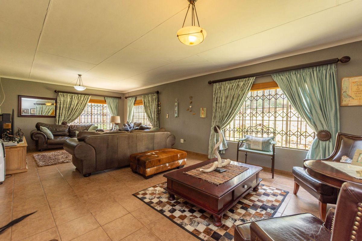 Spacious living room featuring tiled flooring, large windows with security bars, and classic pendant lighting, offering a comfortable and functional family space.