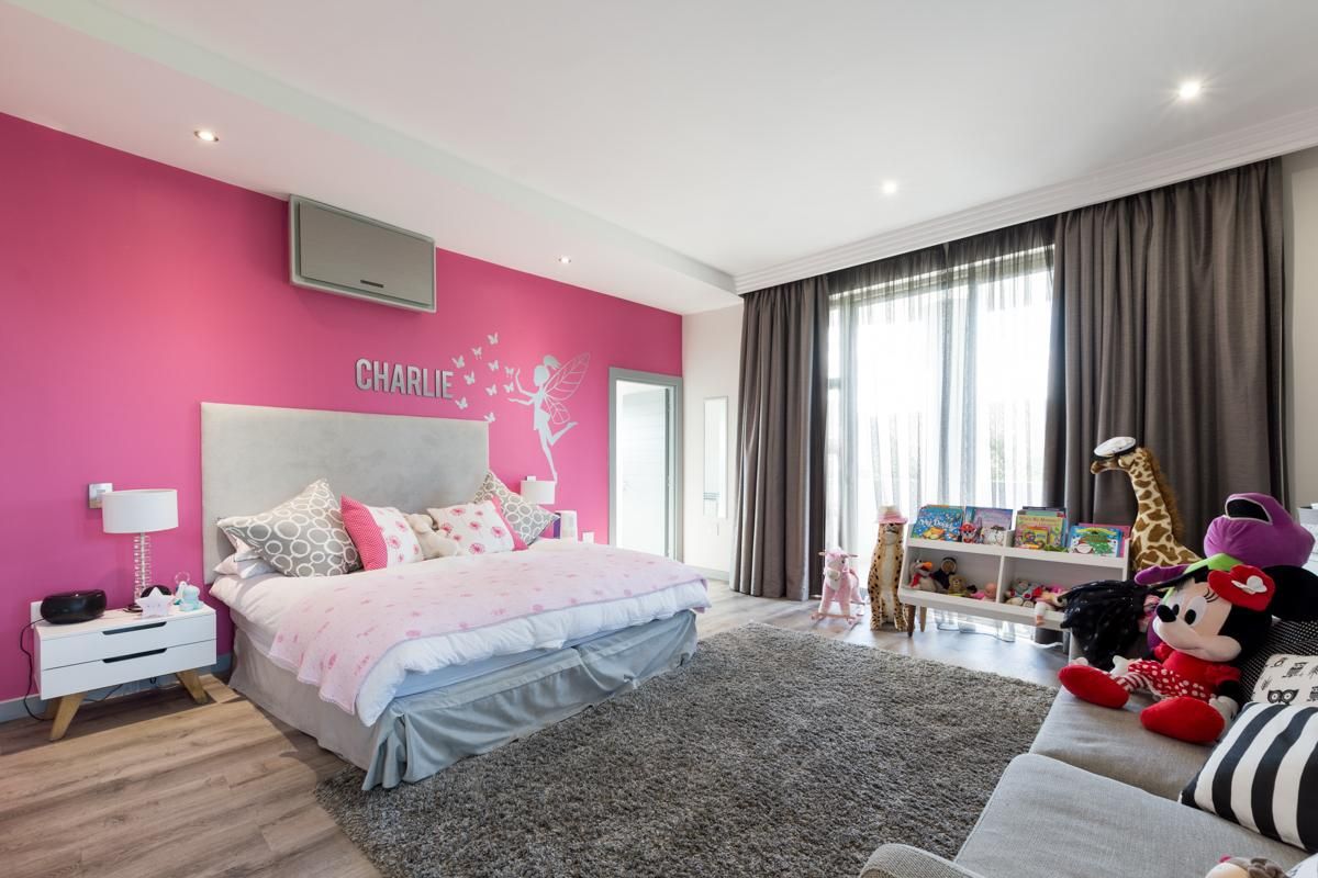 A spacious bedroom featuring recessed ceiling lighting, large floor-to-ceiling curtains, and wood-look flooring, providing a bright and comfortable living space.
