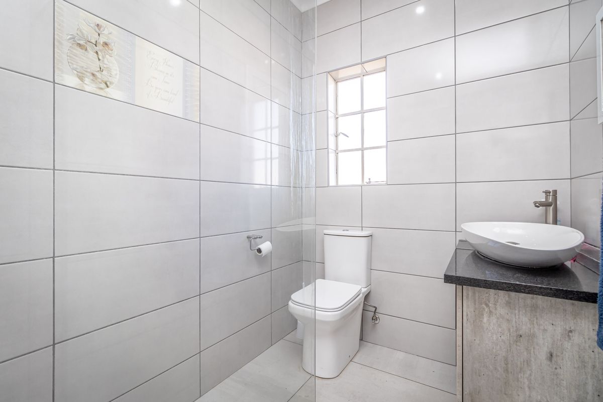 Modern bathroom featuring large format wall tiles, a contemporary vessel sink on a stone vanity, and a glass shower partition.