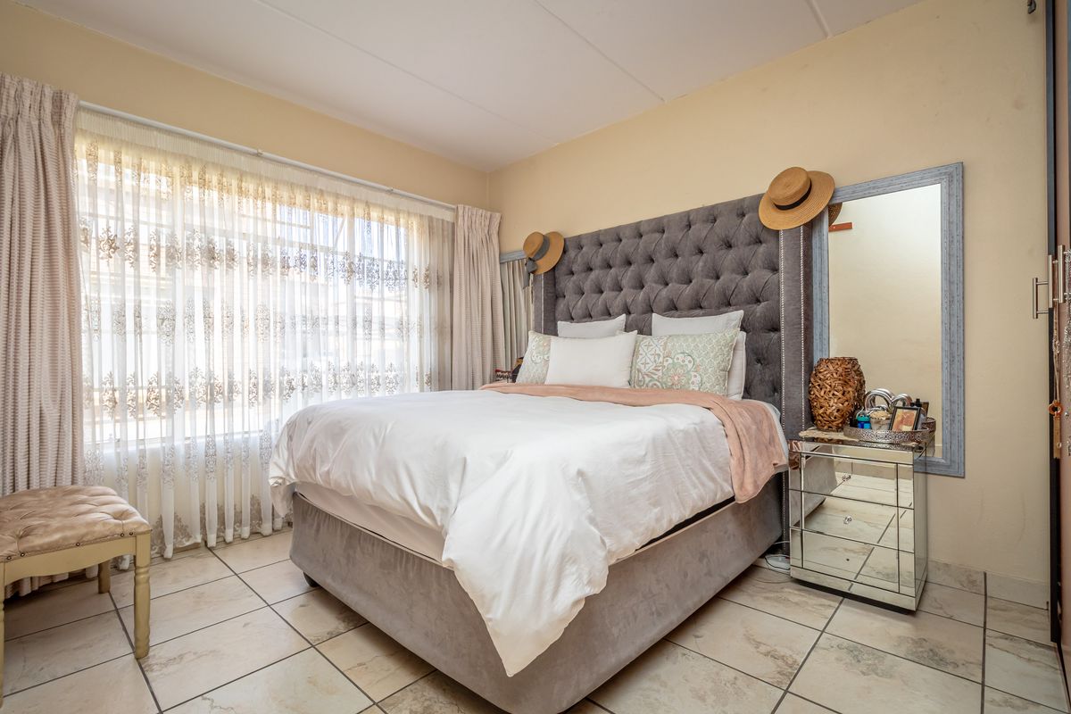 A well-lit bedroom featuring tiled flooring and large windows with curtain treatments, providing a comfortable and functional living space.