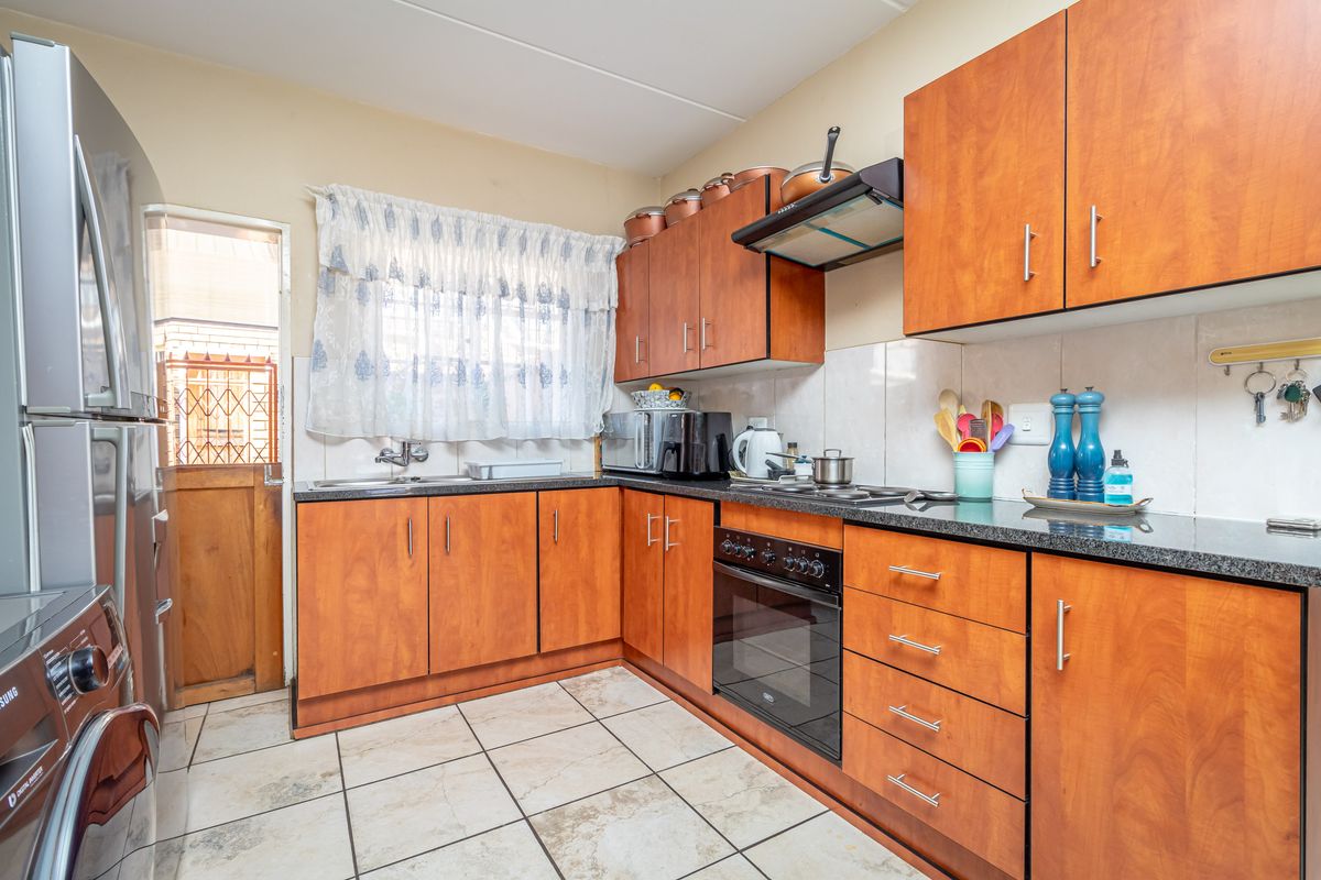 Functional kitchen featuring wood-look cabinetry, granite countertops, built-in oven, extractor fan, and direct access to an exterior door.