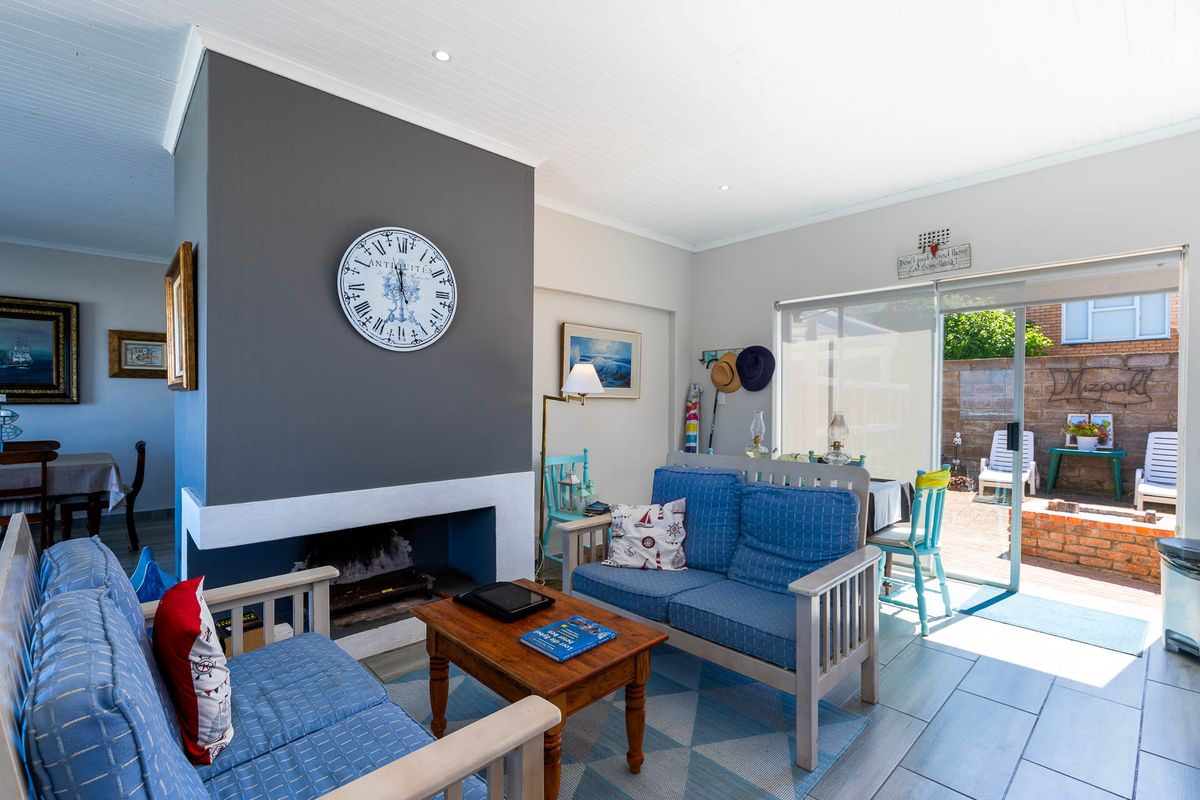 A bright living room featuring a central fireplace with a dark accent wall, tiled flooring, and sliding glass doors leading to an outdoor patio area.