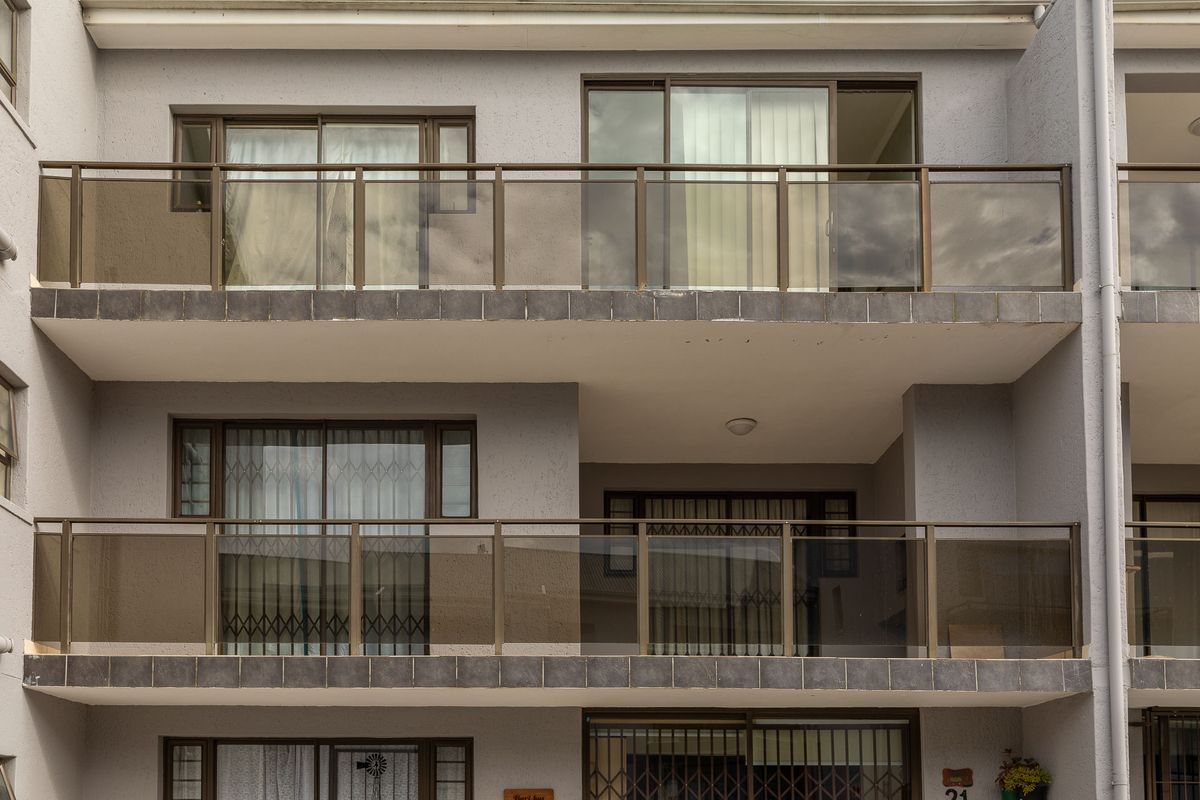 Exterior view of an apartment building featuring multiple levels with private balconies, sliding glass doors, and metal railings.