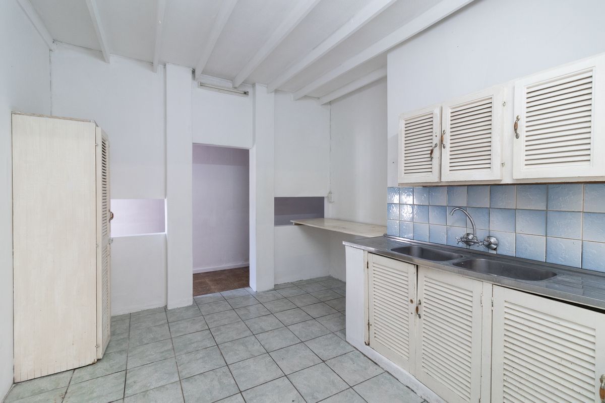 A functional kitchenette area featuring built-in cabinetry, a stainless steel double sink, and tiled flooring, offering a basic workspace for office staff.