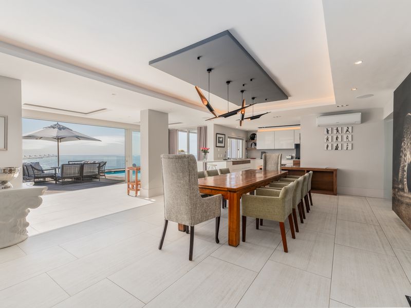 Spacious open-plan dining and kitchen area featuring modern recessed lighting, sleek cabinetry, and seamless flow to an outdoor patio with ocean views.