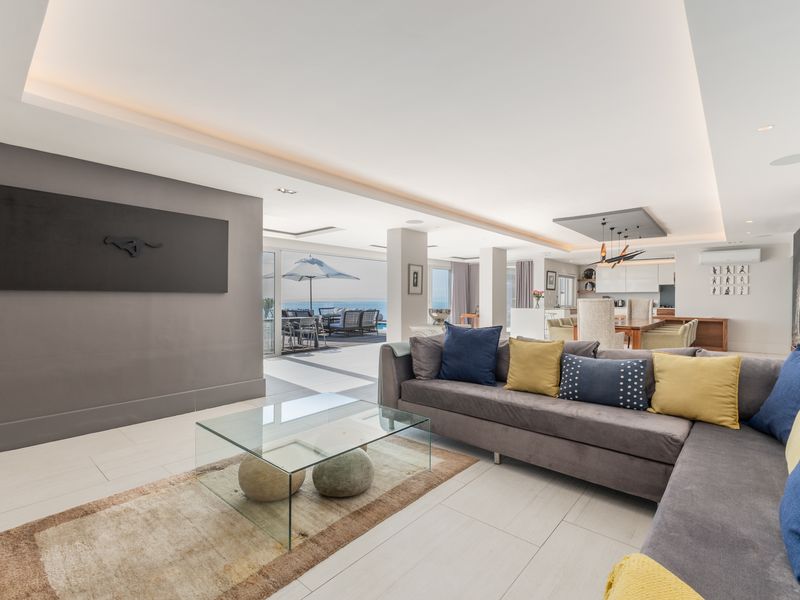 Spacious open-plan living area featuring recessed ceiling lighting, large format floor tiles, and seamless flow to the outdoor patio and pool area.