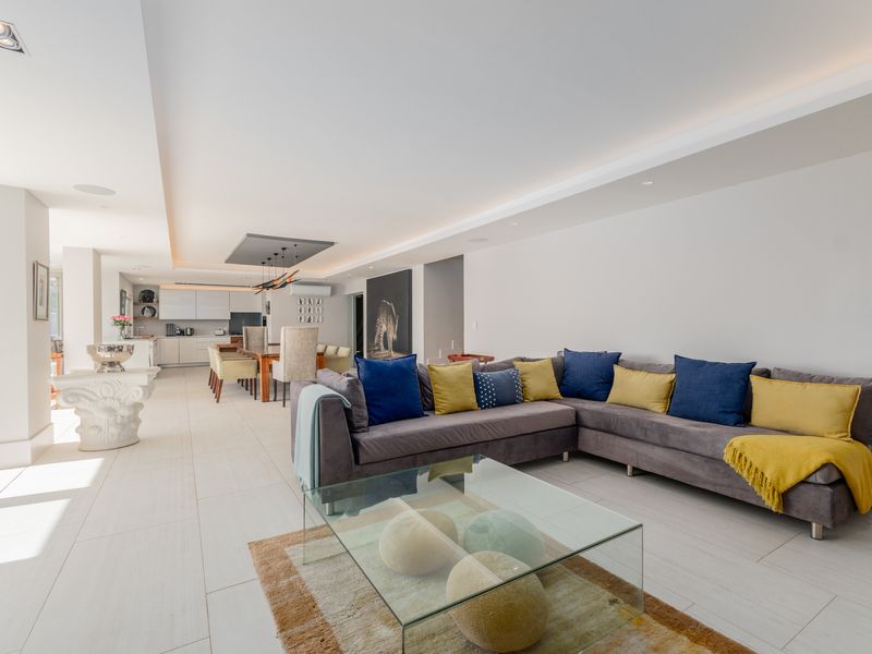 Spacious open-plan living and dining area featuring modern recessed ceiling lighting, large format floor tiles, and a seamless flow to the kitchen.