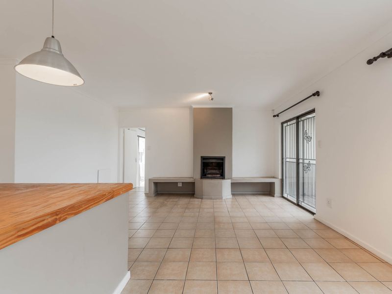 Spacious open-plan living area featuring tiled floors, a central built-in fireplace with bench seating, and sliding door access to the exterior.
