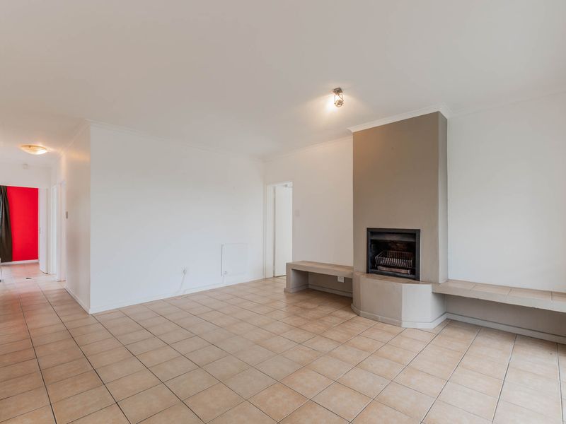 Spacious living area featuring neutral tiled flooring and a prominent built-in fireplace with integrated bench seating.