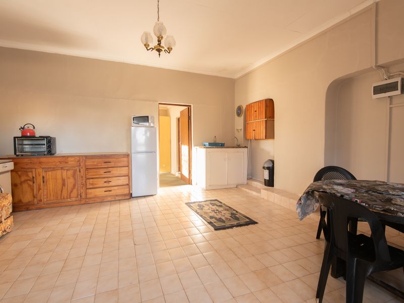 Open plan living and kitchen area featuring tiled flooring, built-in cabinetry, and a sink, offering a functional space with potential for modernization.