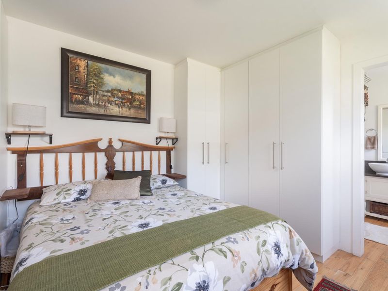 A well-maintained bedroom featuring built-in wardrobes, timber flooring, and an adjoining en-suite bathroom.