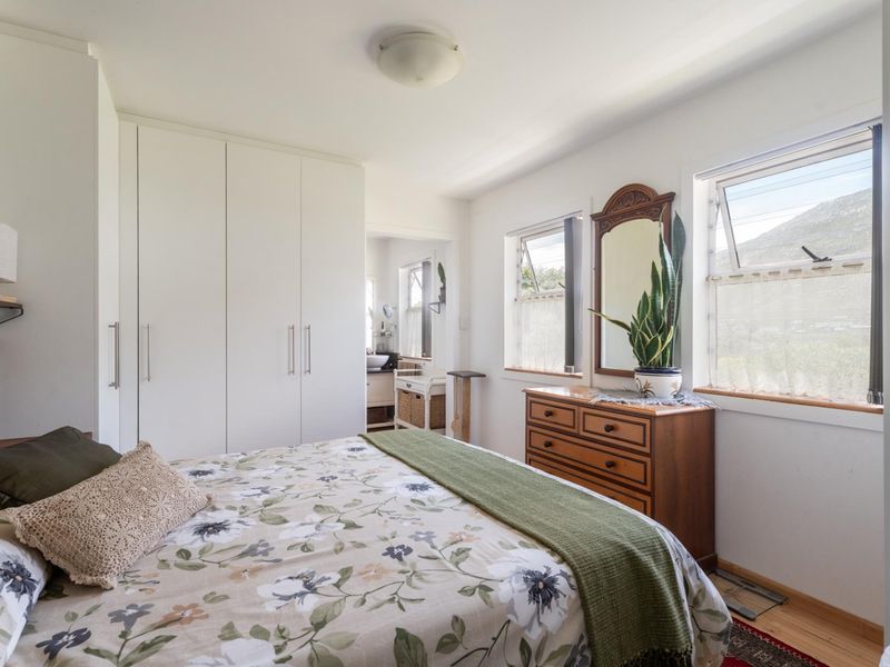 A well-lit bedroom featuring built-in cupboards and dual top-hung windows with views, providing a functional and comfortable living space.