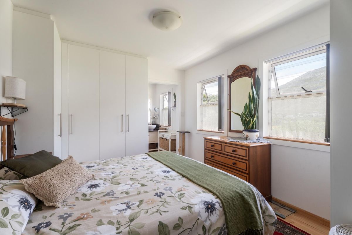 A well-lit bedroom featuring built-in cupboards and dual top-hung windows with views, providing a functional and comfortable living space.