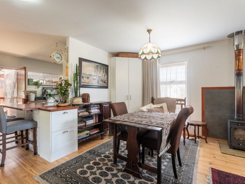 Open-plan living and dining area featuring timber flooring, a wood-burning stove, and a functional kitchen island with integrated storage.