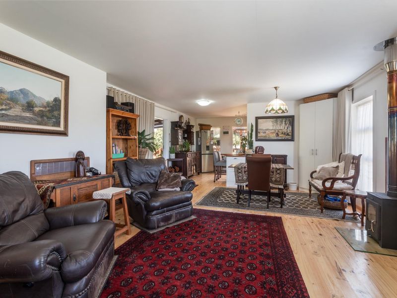 Spacious open-plan living and dining area featuring timber flooring and a prominent wood-burning stove, flowing into a functional kitchen space.