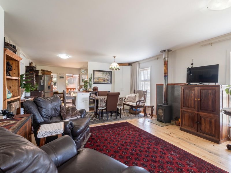 Spacious open-plan living and dining area featuring timber flooring, a wood-burning stove, and a functional kitchen layout.