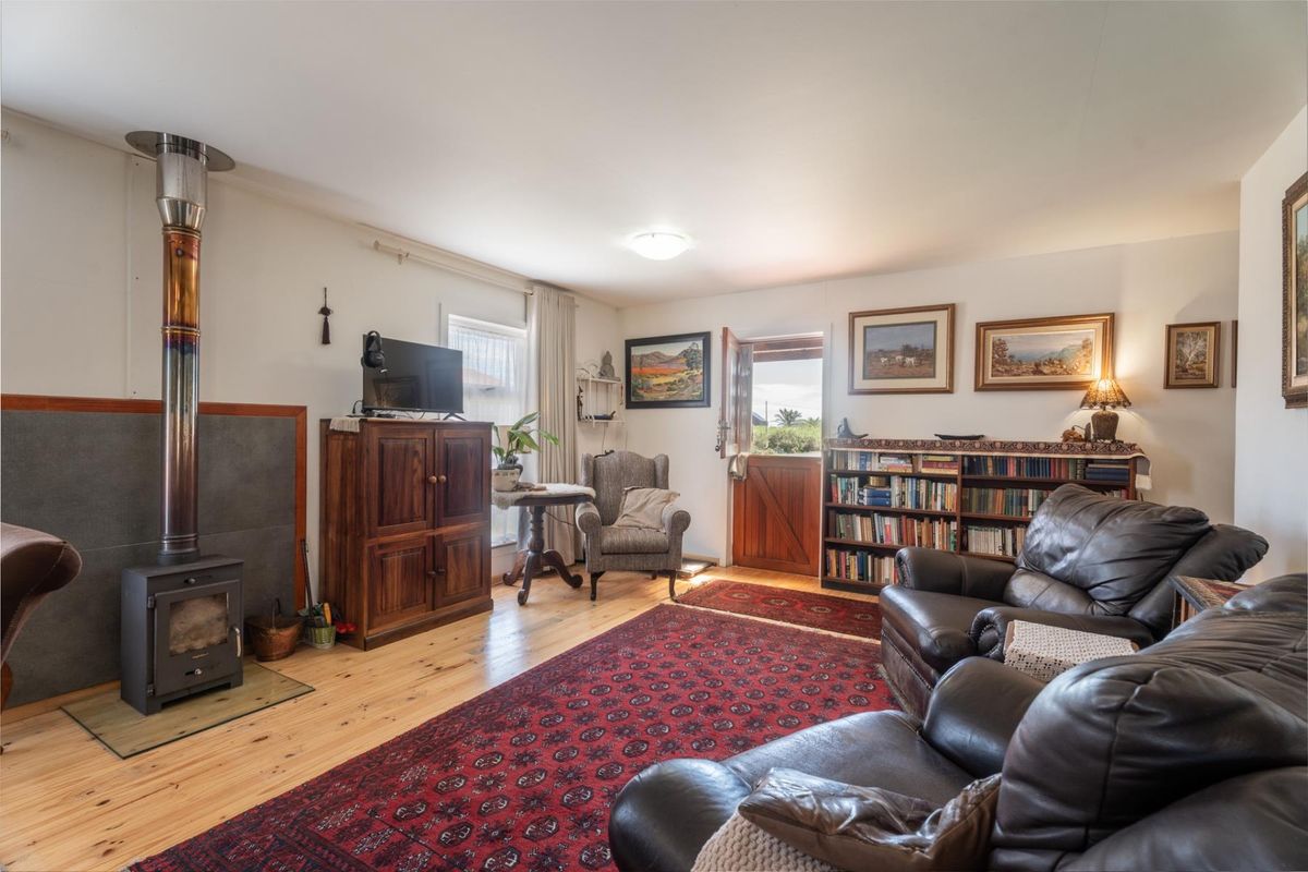 A cozy living room featuring timber flooring and a prominent wood-burning stove with a flue pipe, leading out through a stable-style door.