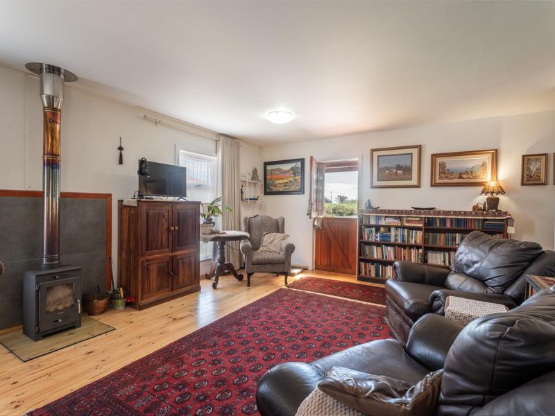 A cozy living room featuring timber flooring and a prominent wood-burning stove with a flue pipe, leading out through a stable-style door.