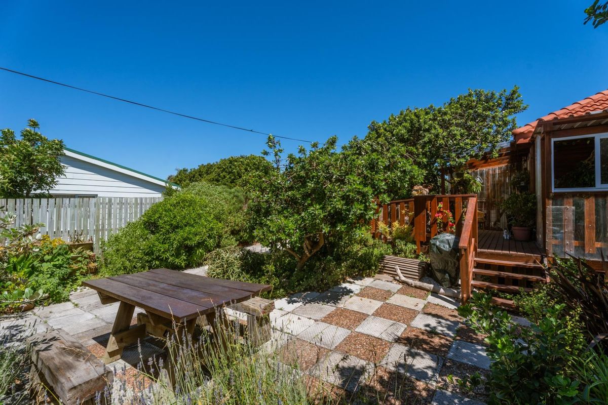 A private rear garden featuring a paved patio area, timber decking, and stairs leading to the main dwelling.