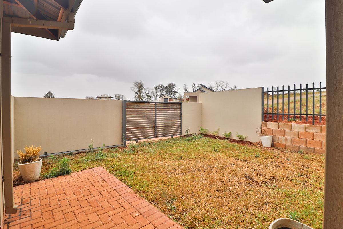A private rear garden featuring a brick-paved patio area, perimeter boundary walls, and a slatted metal gate.