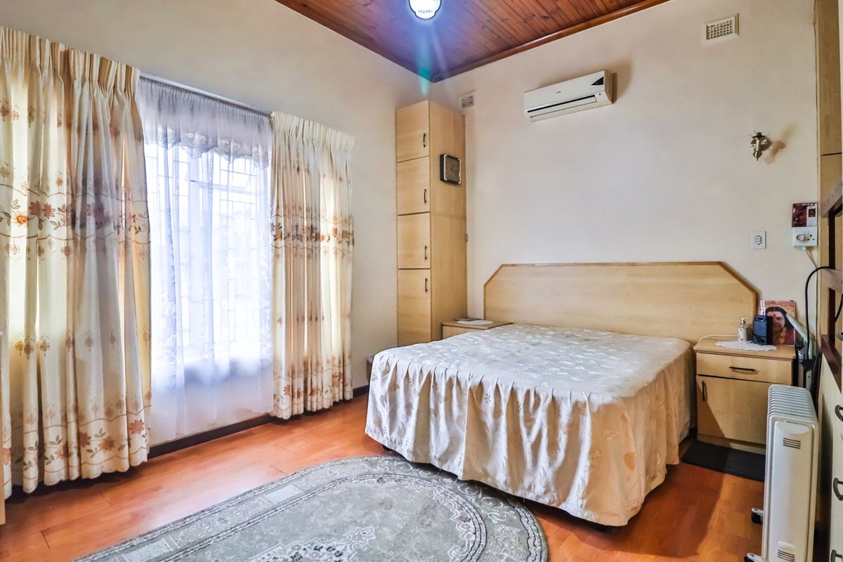 A bedroom featuring timber ceiling paneling, built-in cabinetry, and a wall-mounted air conditioning unit.
