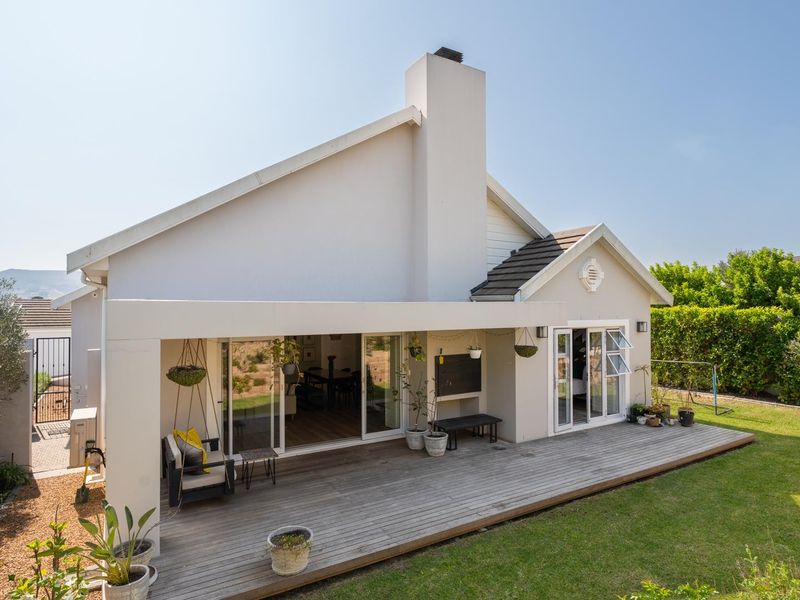 Rear view of the property featuring a spacious timber deck, built-in outdoor fireplace, and large sliding doors leading into the home.
