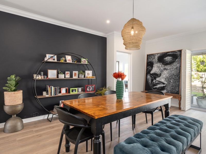 A well-lit dining area featuring timber-look flooring, crown molding, and direct access to the outdoor patio through a sliding glass door.