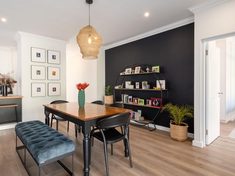 Open-plan dining area featuring timber-look flooring, crown molding, and recessed lighting, seamlessly connected to a modern kitchen with built-in cabinetry.
