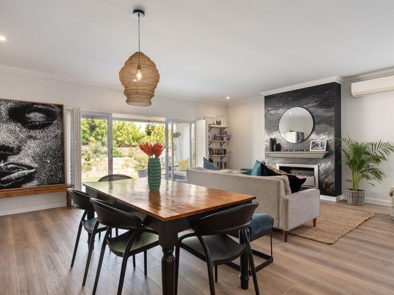 Spacious open-plan living and dining area featuring a modern fireplace, split-system air conditioning, and large sliding doors opening to the garden.