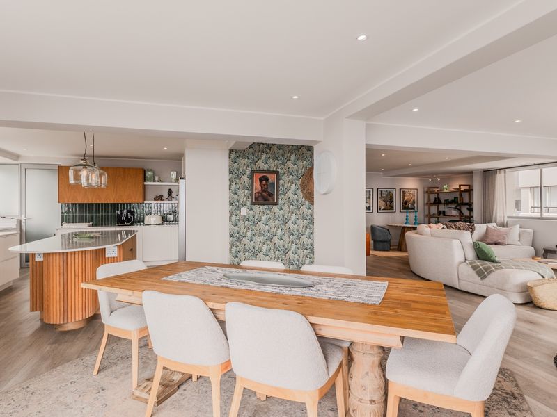 Spacious open-plan living area featuring a modern kitchen with a curved island, dining space, and comfortable lounge area with neutral finishes.
