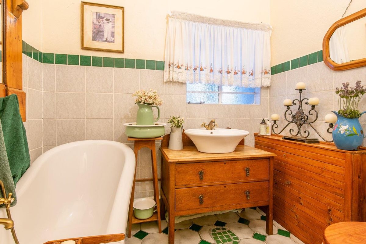 A vintage-style bathroom featuring a classic clawfoot bathtub, a vessel sink set on a wooden vanity, and decorative wall tiling.
