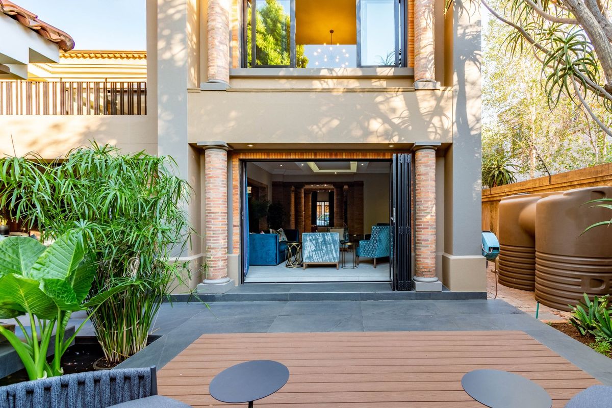 Rear view of the property featuring a paved patio area, composite decking, and large folding doors leading into the open-plan living space.