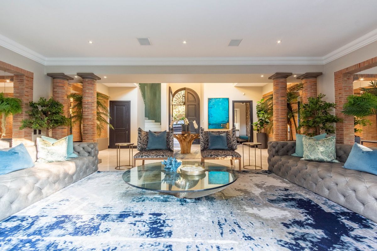 Spacious living area featuring exposed brick columns, recessed lighting, and elegant arched entryway, creating a sophisticated and open atmosphere.