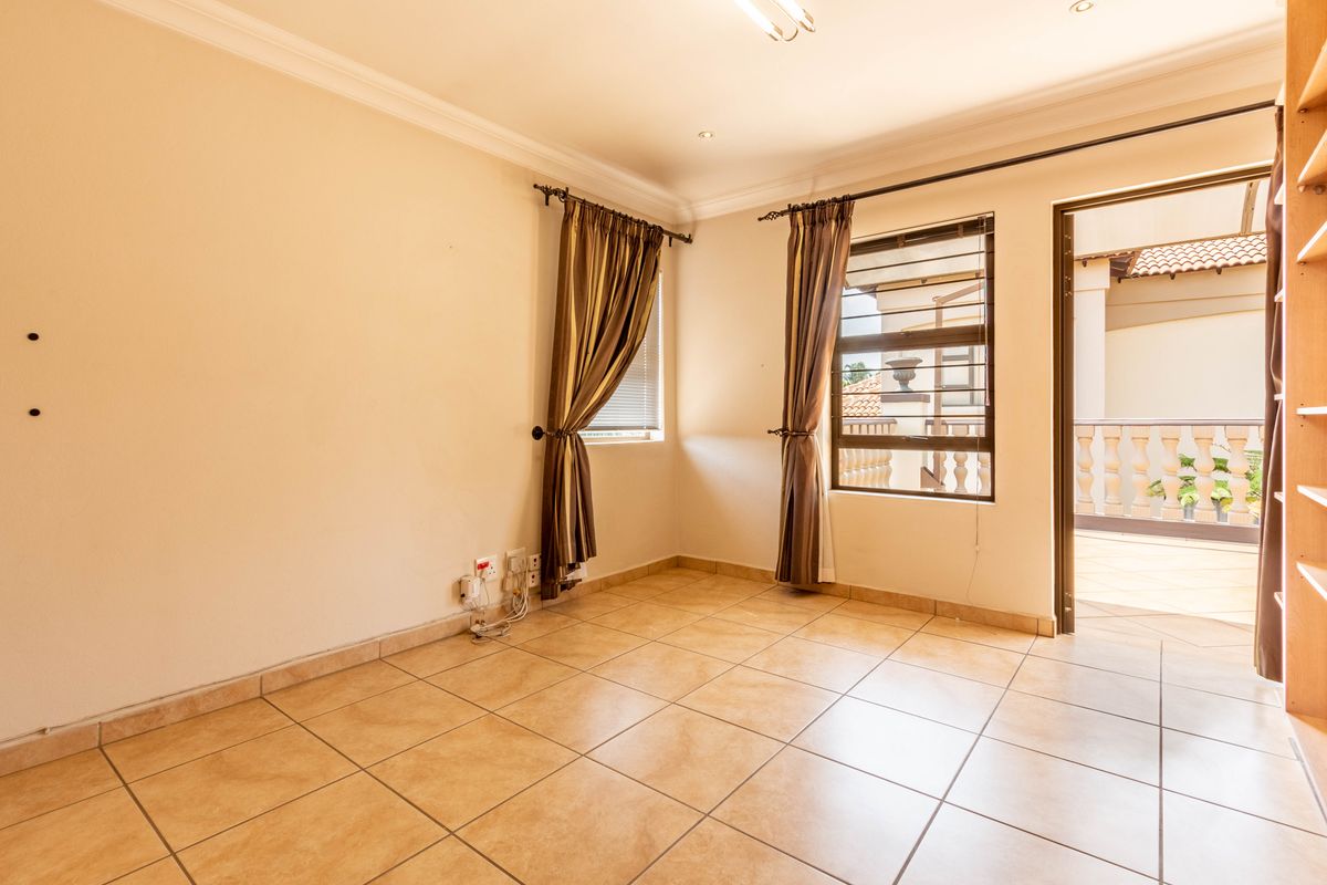 A bright, tiled bedroom featuring built-in shelving and direct access to an outdoor balcony through a glass door.